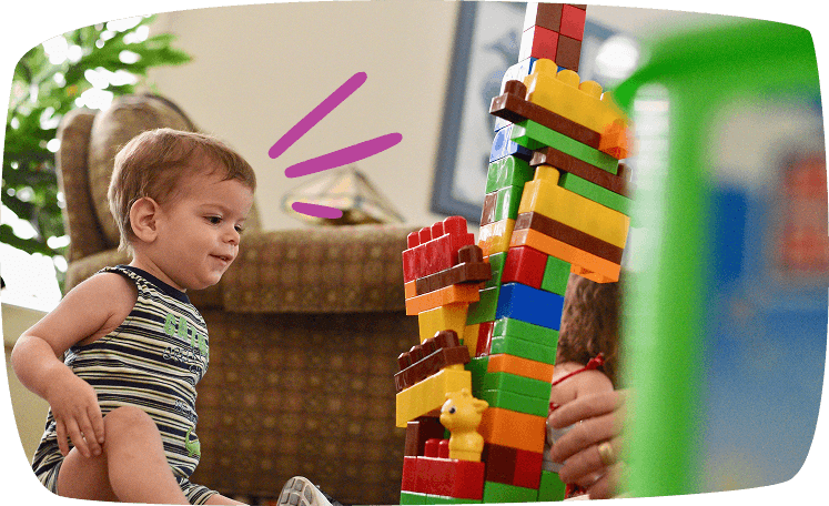 Niño pequeño observando asombrado una torre de bloques de construcción de colores