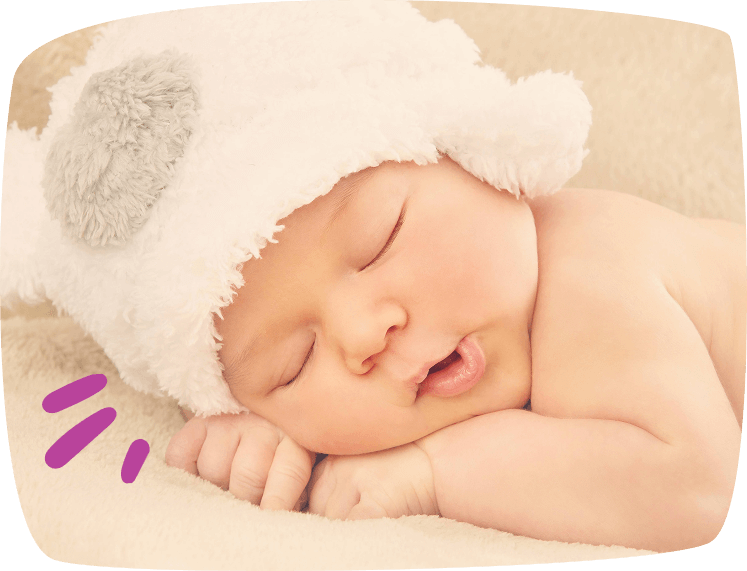 Bebé dormido con gorro blanco sobre una manta suave.