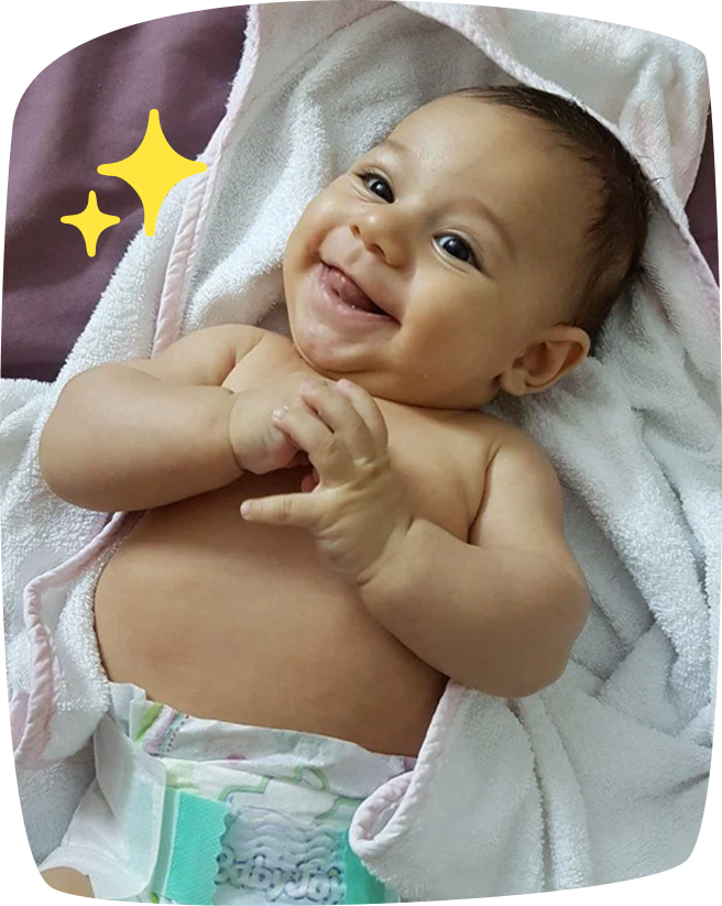 Bebé tumbado sobre una toalla blanca, sonriente y usando pañal.