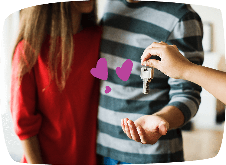 Una mano entrega las llaves a una pareja joven como símbolo de alquilar una habitación para obtener ingresos extra.