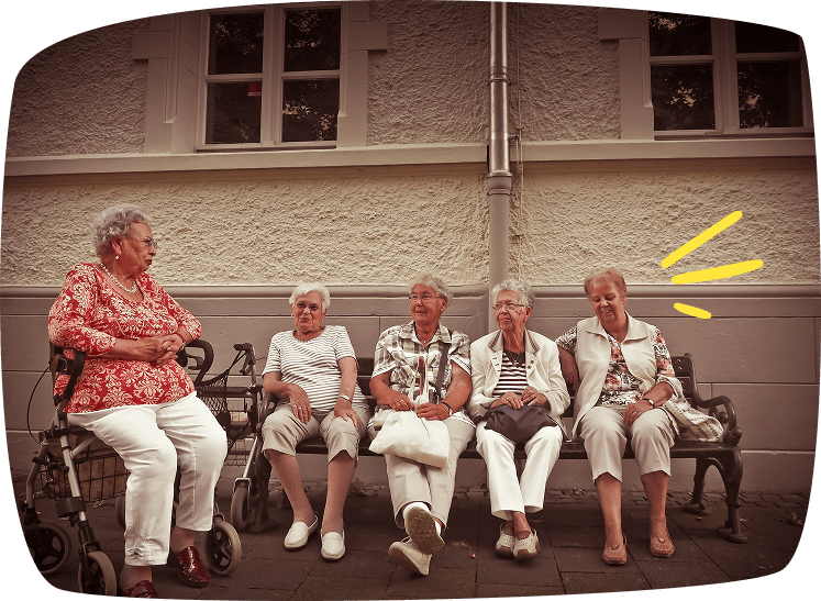 Grupo de personas mayores sentadas en un banco, reflejando el trabajo de cuidador de ancianos durante los fines de semana.