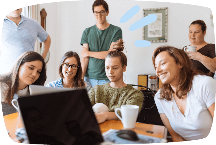 Grupo de personas reunidas alrededor de un portátil en casa, compartiendo ideas para obtener ingresos extra desde casa.