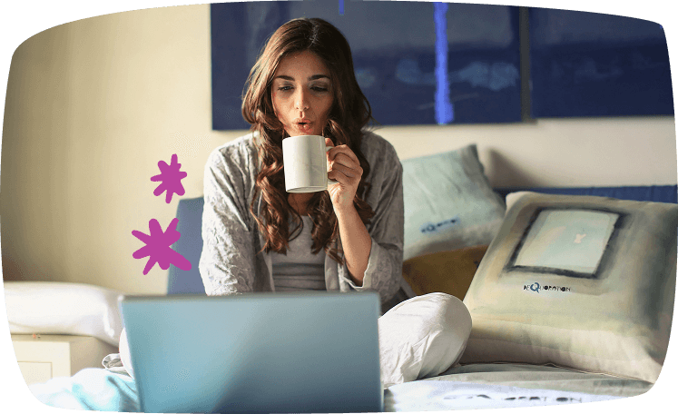 Mujer tomando café mientras trabaja en su portátil desde la cama, ilustrando trabajos flexibles de fin de semana.