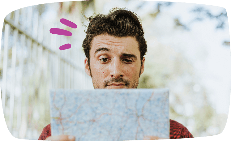 Hombre joven observando un mapa con expresión curiosa, simbolizando el trabajo de guía turístico en fines de semana.