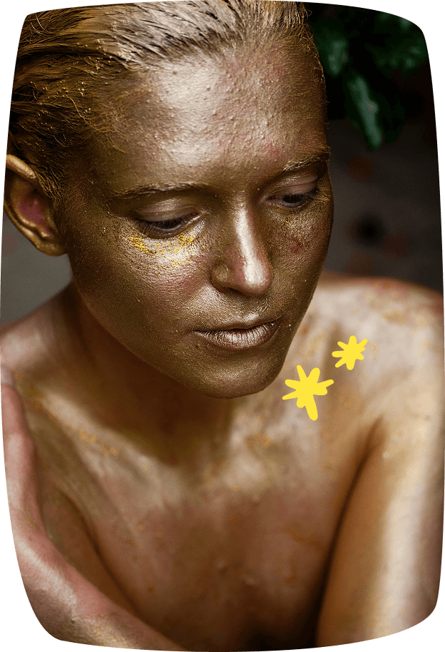 Modelo artística con el cuerpo pintado de dorado, posando para sesiones de pintura o dibujo artístico.