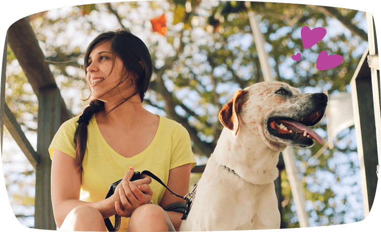 Mujer sentada junto a su perro en un parque, representando el trabajo de paseador de mascotas para ingresos adicionales.