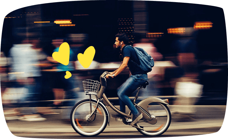 Repartidor en bicicleta circulando por una calle de ciudad, transportando una mochila para entregas a domicilio.