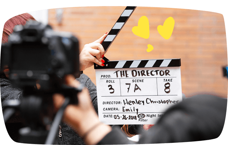 Persona sosteniendo una claqueta de cine durante una grabación, rodeada de cámaras y equipo técnico.