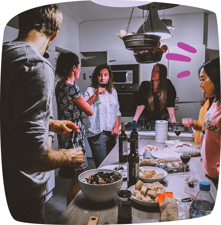 Grupo de estudiantes compartiendo una cena en una cocina común, conversando y disfrutando del momento.