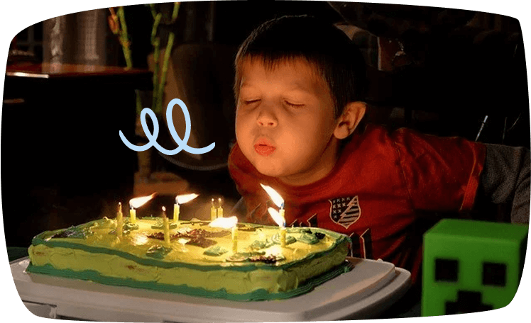 Niño soplando las velas de su tarta de cumpleaños con ilusión.