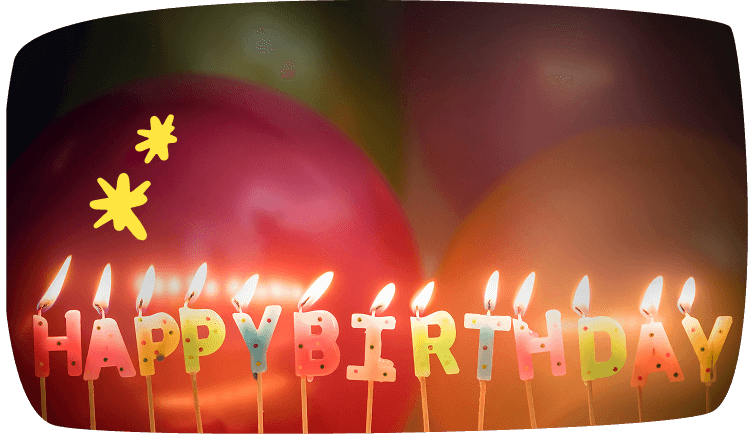 Velas encendidas con letras 'Happy Birthday' y globos de colores de fondo.