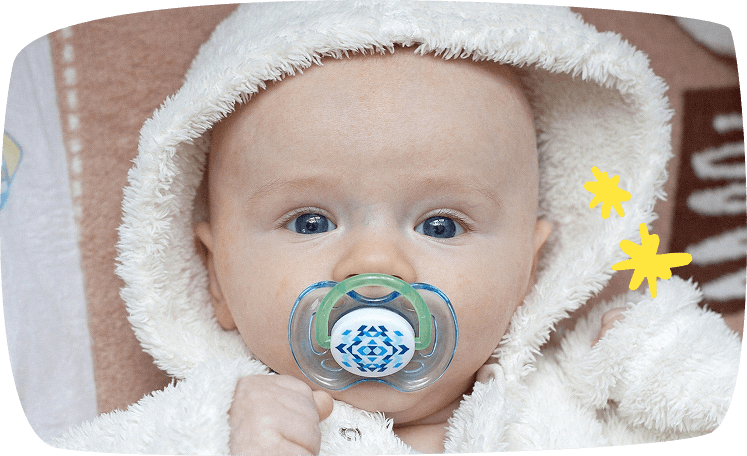 Bebé envuelto en abrigo de peluche blanco con chupete azul y verde.