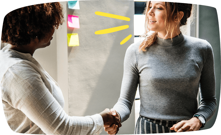 Dos mujeres dándose la mano tras llegar a un acuerdo, simbolizando la firma de un contrato de niñera.