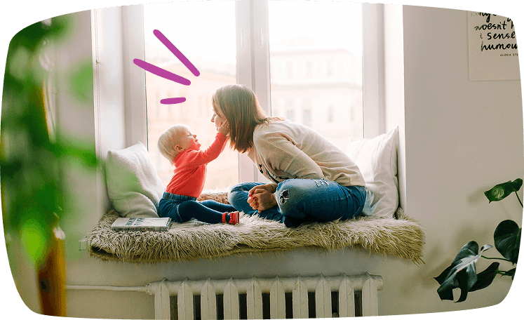 Madre e hijo jugando con ternura en la ventana, el bebé le toca la nariz con cariño.