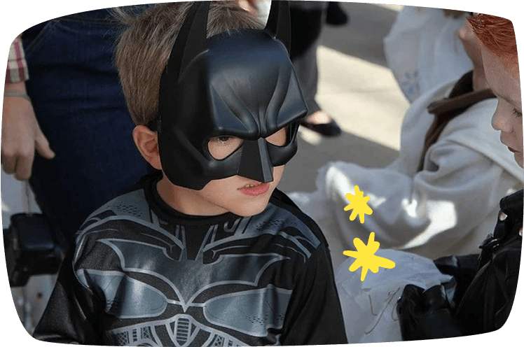 Niño disfrazado de Batman en una fiesta de cumpleaños con otros niños disfrazados.