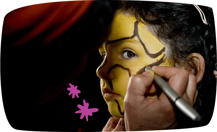 Niña sonriente mientras le pintan la cara con un pincel durante una fiesta infantil.