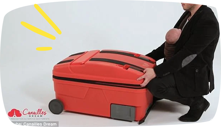 Padre preparando maleta La Multi mientras sostiene a un bebé en porteo