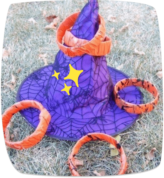 Gorro de bruja morado con anillos naranjas para juego de puntería en el césped durante una fiesta de Halloween.