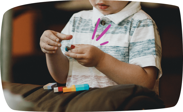 Niño pequeño jugando con bloques de construcción de colores, desarrollando la motricidad fina y la concentración.