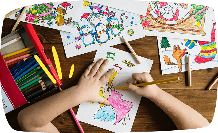 Niño coloreando dibujos navideños con lápices de colores sobre una mesa de madera, rodeado de ilustraciones festivas.
