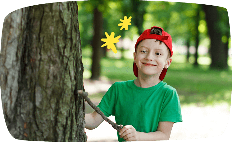 Niño con gorra roja jugando con un palo en el parque, disfrutando de un juego al aire libre.