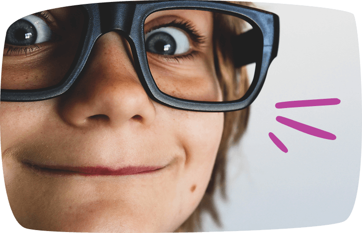 Primer plano de un niño con gafas grandes sonriendo, destacando la creatividad y el humor en el juego.