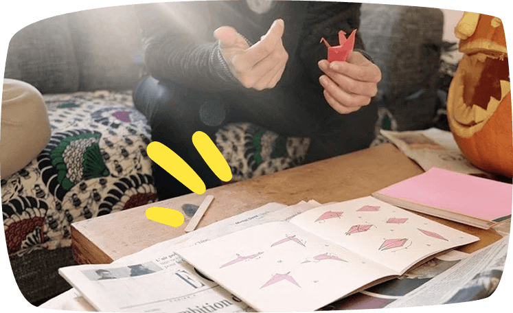 Persona realizando una figura de origami con un tutorial en papel, fomentando la destreza manual y la concentración en los niños.