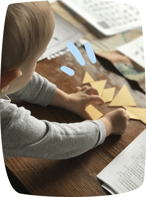 Niño pequeño jugando con un tangram de piezas de papel sobre la mesa