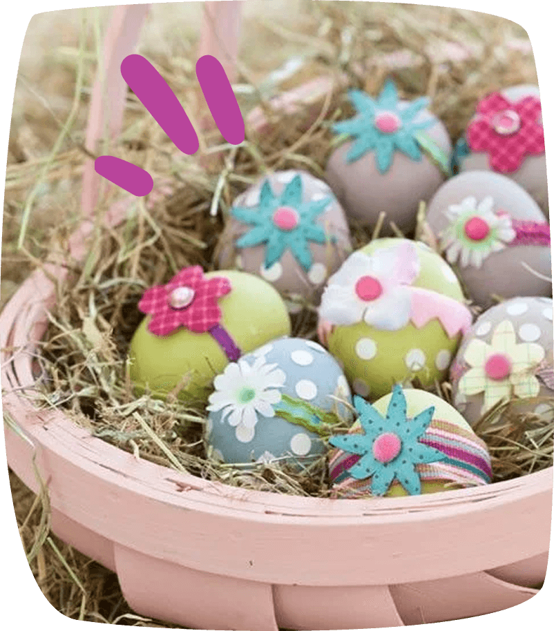 "Huevos de Pascua decorados con flores de fieltro y lunares, colocados en una cesta con paja natural."