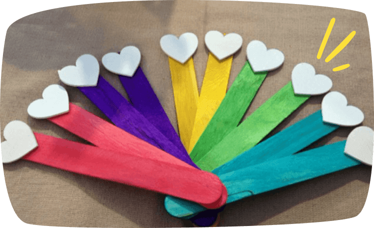 Abanico hecho con palitos de colores decorados con corazones blancos.