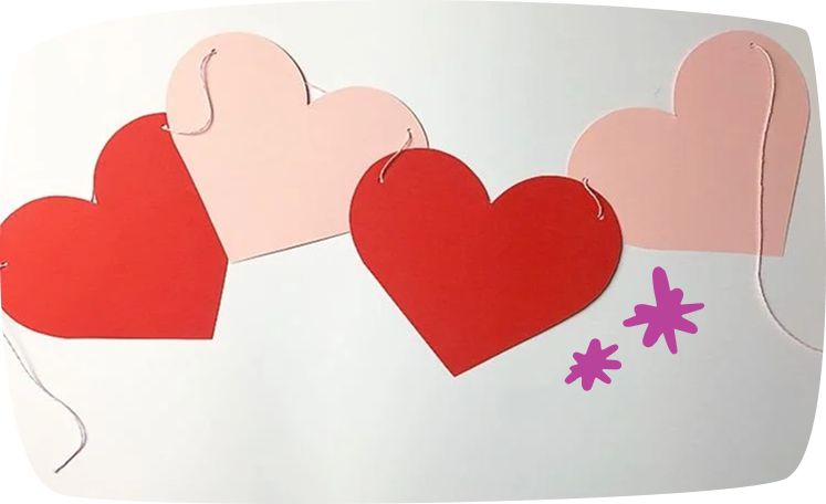 Guirnalda de corazones rojos y rosas hechos de cartulina, unidos con hilo decorativo.