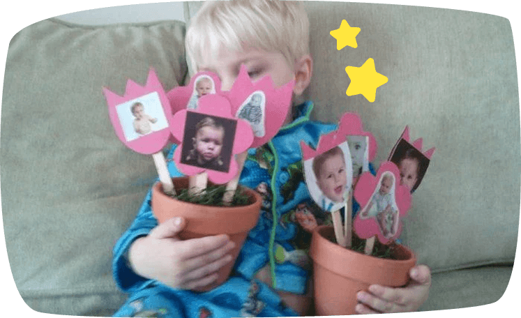 Niño sujetando macetas con flores de papel y fotos personales.