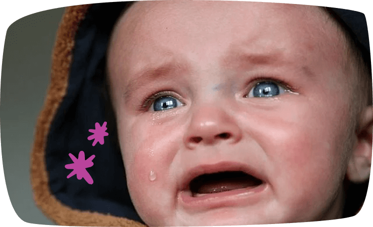 Bebé llorando con capucha y lágrimas en el rostro.