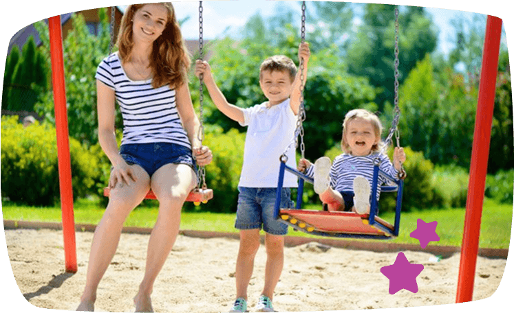 Niñera jugando con dos niños en un columpio en el parque, mostrando una relación alegre y activa al aire libre.