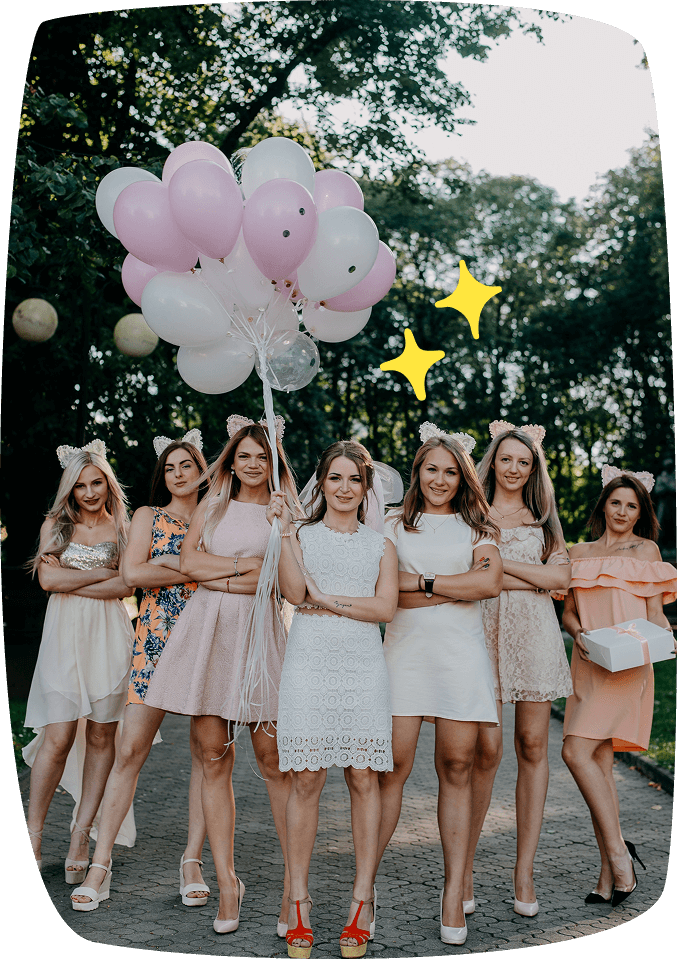 Mujeres jóvenes vestidas para una celebración, sujetando globos de colores en un parque.