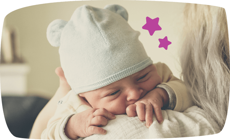 Bebé durmiendo plácidamente con un gorro blanco sobre una manta suave.