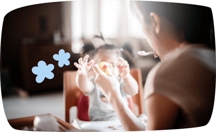Cuidadora dando de comer a un bebé con una cucharita, representando las tareas básicas de alimentación dentro de las funciones de una niñera.