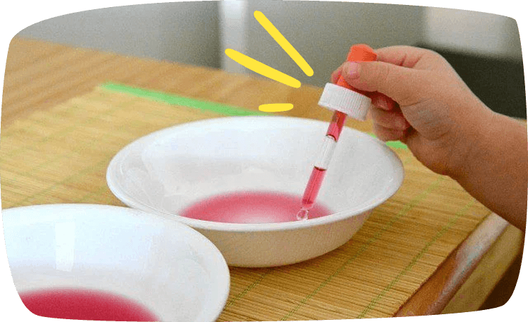 Niño realizando una actividad Montessori de decantación con gotero y agua teñida