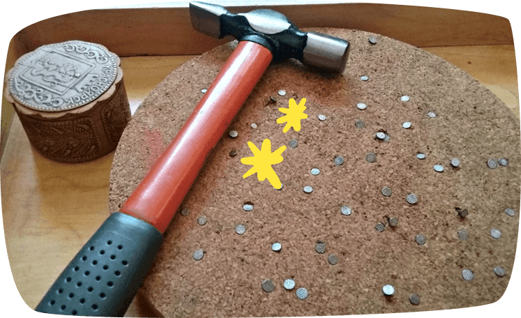 Martillo y clavos sobre tabla de corcho para actividad Montessori de coordinación