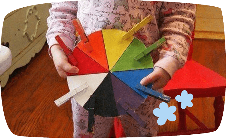 Niño jugando con una rueda de colores y pinzas en actividad Montessori