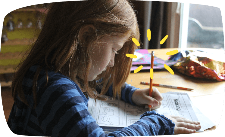 Niña pelirroja concentrada dibujando en un cuaderno, ideal para juegos tranquilos y educativos.