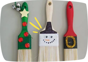 Manualidades con brochas decoradas como personajes navideños: un árbol, un muñeco de nieve y Papá Noel.
