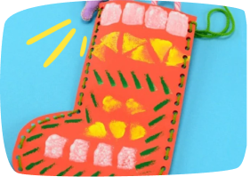 Calcetín de Navidad hecho con cartulina decorada y perforaciones para pasar lana, manualidad infantil colorida y festiva.