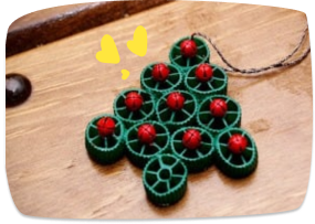 Adorno de árbol navideño en forma de abeto hecho con pasta de rueda pintada de verde y bolitas rojas.