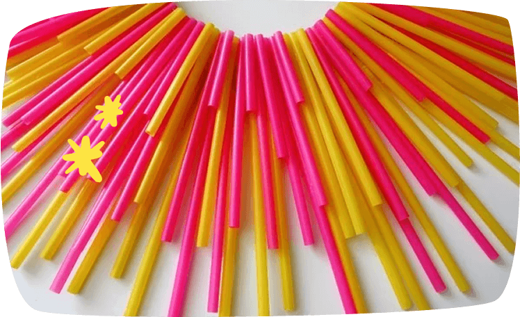 Pajitas rosas y amarillas colocadas en forma de abanico radial, listas para una manualidad decorativa.
