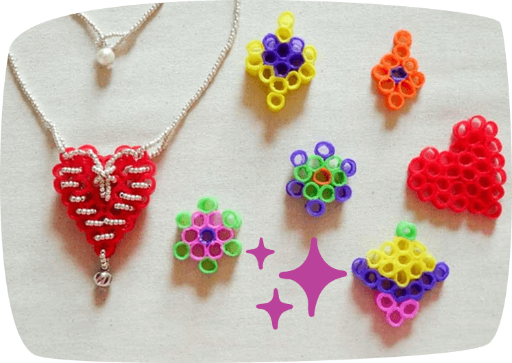 Colgantes en forma de corazón y flores hechos con trozos pequeños de pajitas de colores y cordón decorativo.