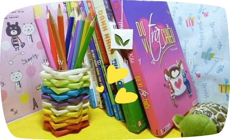 Portalápices colorido hecho con pajitas entrelazadas, decorando un escritorio con libros infantiles.