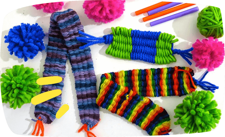 Manualidades tejidas con lana de colores y pajitas, acompañadas de pompones y decoración vibrante.