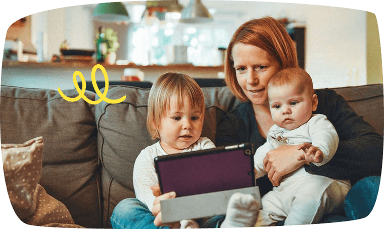 Madre con sus dos hijos pequeños viendo una tablet en el sofá
