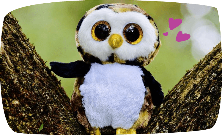 Peluche de búho de colores marrón y blanco, con ojos grandes y brillantes, posado en la rama de un árbol.